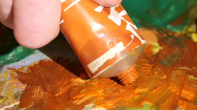 画家在调色板上挤出橙色的油彩，特写慢动作视频下载