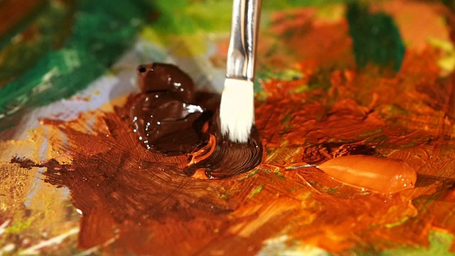 画家在调色板上混合了棕色和橙色的油画，特写，慢动作视频下载