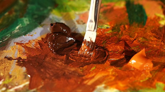 画家在调色板上混合了两种棕色和橙色的油画，特写，慢动作视频下载