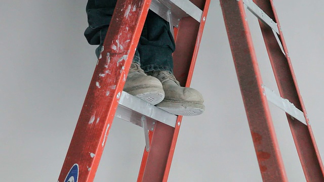 一个人站在梯子上的特写。视频下载