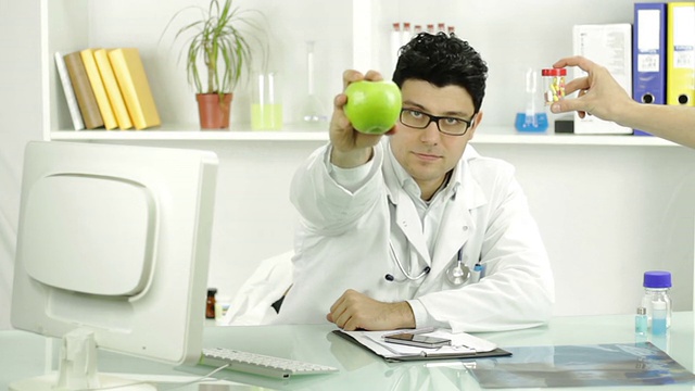 年轻医生认为健康的苹果或提供水果的药丸视频素材