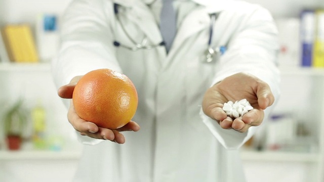 医生拿着水果和药丸的手健康的选择视频下载