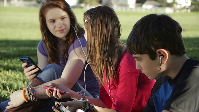 外面的青少年用智能手机分享音乐视频下载