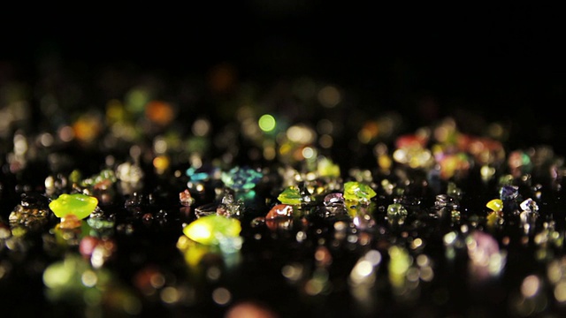 黑色的桌子上散落着钻石形状的彩色晶体。锅。视频素材