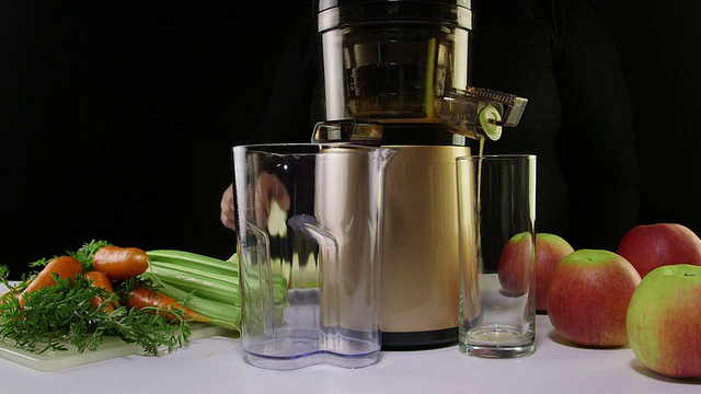 用冷压榨汁机从胡萝卜和芹菜中榨出鲜榨汁视频素材