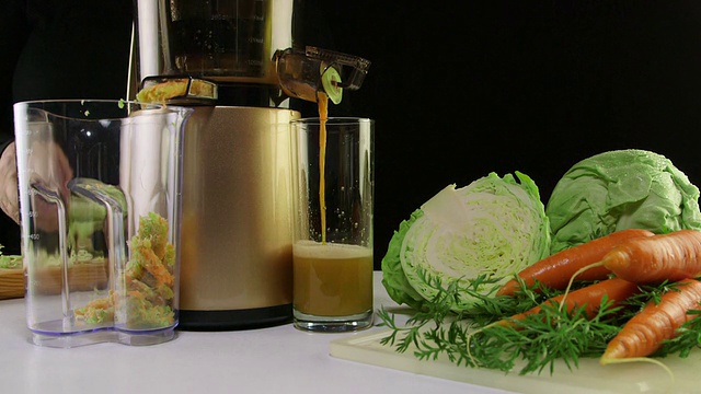 用冷榨榨汁机从胡萝卜和卷心菜中榨出鲜榨汁视频素材