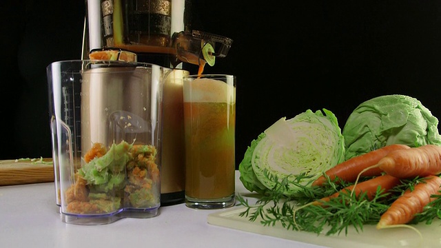 多莉:用冷榨汁机将胡萝卜和卷心菜榨汁制成蔬菜汁的工艺视频素材