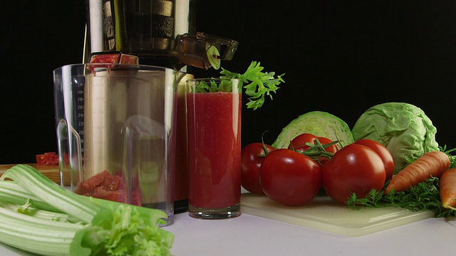 多莉:鲜榨番茄汁和冷榨榨汁机在黑色的背景视频素材