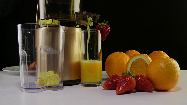 用咀嚼榨汁机榨取新鲜的草莓和橙汁视频下载