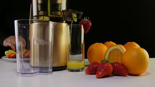 多莉:用咀嚼榨汁机榨取新鲜的草莓和橙汁视频素材
