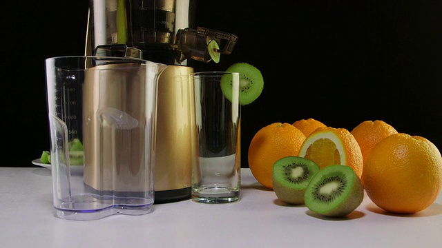 多莉:用橙子和猕猴桃榨汁的冷压榨汁机视频素材