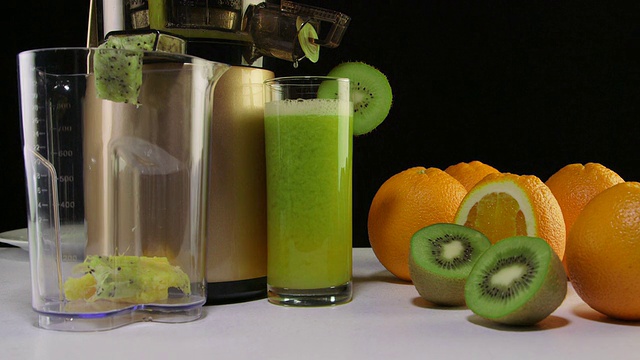 用咀嚼榨汁机榨出新鲜橙汁和猕猴桃汁视频素材