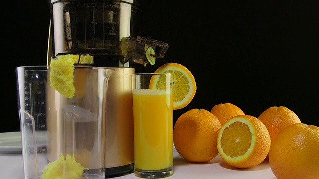多莉:鲜榨橙汁，冷榨榨汁机，黑色背景视频下载