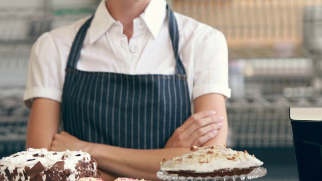快乐的服务员在她的纸杯蛋糕旁边对着镜头微笑视频素材