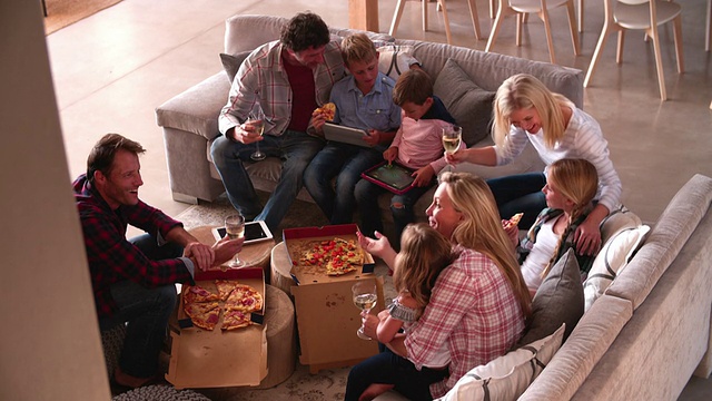 家庭在沙发上放松，外卖披萨和葡萄酒视频素材