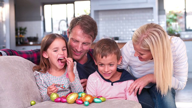 孩子们坐在沙发上和父母一起吃复活节彩蛋视频素材