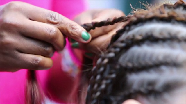 传统的非洲辫子。女人在街上给女孩编辫子。视频素材
