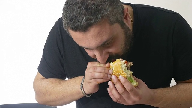 一个饥饿的人正在狼吞虎咽地吃汉堡包视频素材