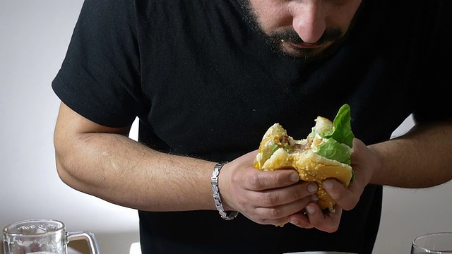 狼吞虎咽的人吃一个XXL汉堡:节食，超重，肥胖，垃圾食品视频素材