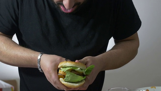 狼吞虎咽的人吃一个XXL汉堡:节食，超重，肥胖，垃圾食品视频素材