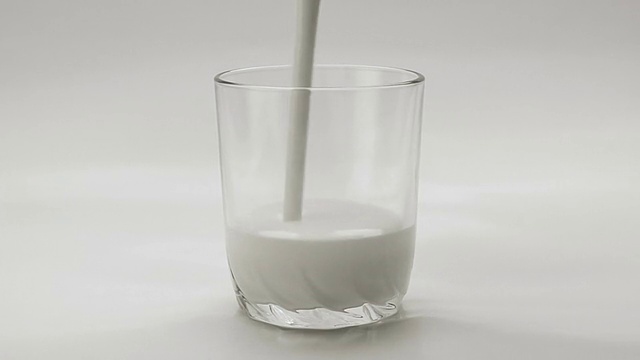 在白色背景的透明玻璃中倒入白色酸奶视频素材