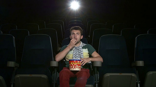 一个快乐的年轻人在空荡荡的电影院看电影视频素材