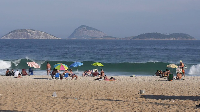 人们在巴西里约热内卢著名的伊帕内玛海滩享受温暖的天气。视频素材