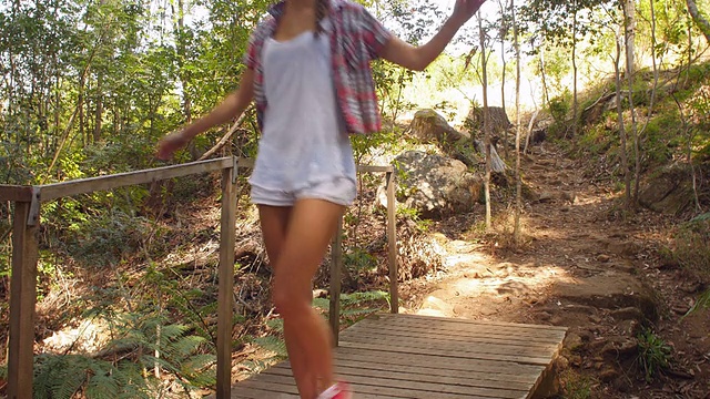 一群朋友穿过森林里的一座小桥视频素材