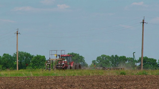 带播种机的农用拖拉机在田间播种作物视频素材