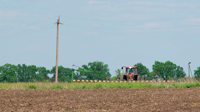 拖拉机与播种机在田间播种作物视频素材
