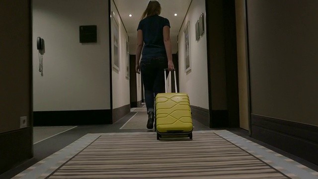 拿着行李箱的女人走在酒店的走廊上视频素材