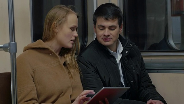 年轻人在移动的地铁列车上使用平板电脑视频素材