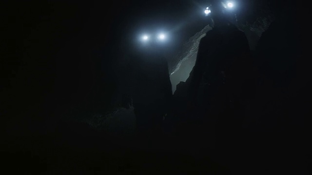 矿工们疲倦地在只有他们的前照灯照亮的黑暗洞穴中搜寻。视频素材