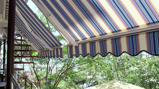 酒店阳台与可伸缩的条纹遮阳篷俯瞰海边视频素材