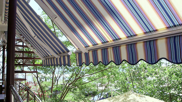 酒店阳台与可伸缩的条纹遮阳篷俯瞰海边视频素材