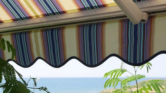 阳台与可伸缩的条纹遮阳篷与海景视频素材