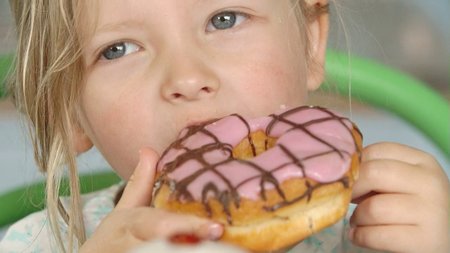 女孩吃冰甜甜圈的特写视频素材
