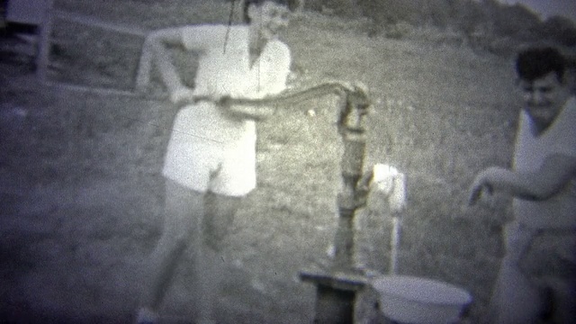 俄克拉荷马州，美国——1943年:一位妇女在抽水，而一位男子在清洗。视频下载