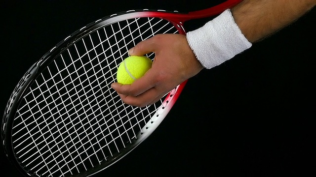 一名网球运动员在击球前手持网球和球拍的慢动作，黑色背景视频下载