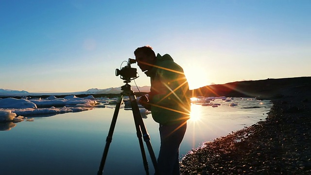 一位摄影师在日出时拍摄冰川泻湖上的冰山。Jokulsarlon河口视频下载