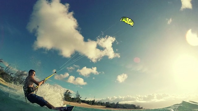 一个年轻人在海洋中乘着风筝冲浪。视频素材