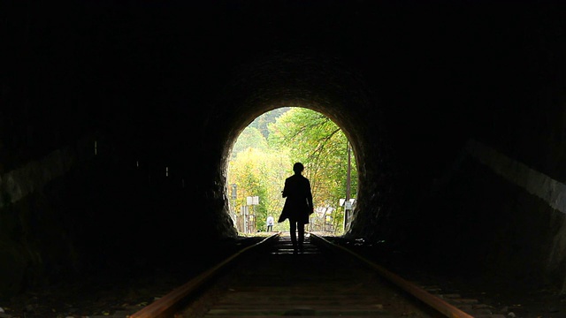 迷路的女人走向黑暗隧道的尽头，前方有光视频素材