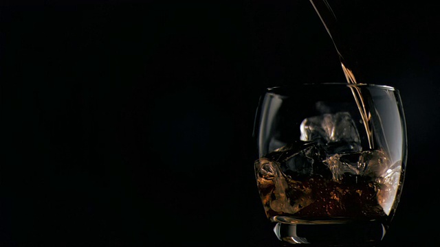威士忌以超慢动作倒入加冰的玻璃杯中视频素材