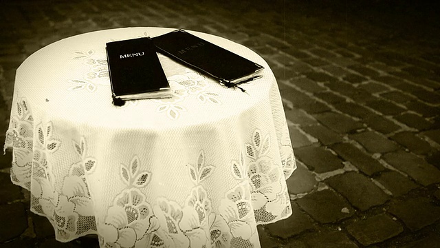 老电影镜头:两份黑色菜单躺在一个咖啡馆的户外桌子上视频素材