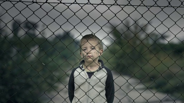 栅栏后的孤独男孩，孤儿或难民营。视频下载