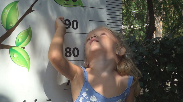 孩子在玩，检查她的身高，母亲测量小女孩的身高视频下载