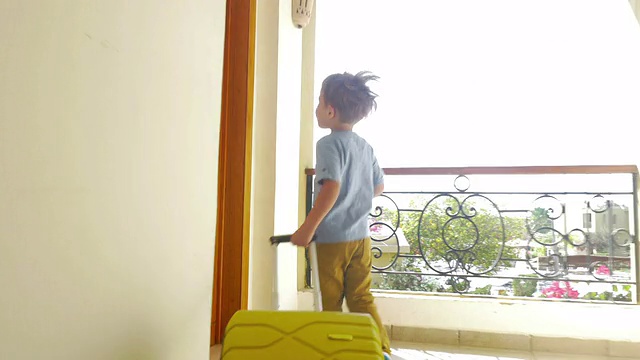孩子拿着滚动袋在酒店走廊上奔跑视频素材