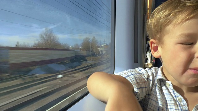 在阳光明媚的日子里，小男孩望着火车窗外视频素材