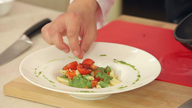 厨师将炸红圣女果与绿香蒜沙司放在盘子里视频素材