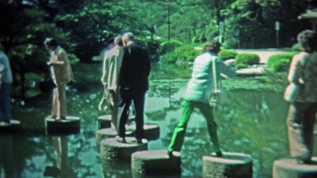 1972年:人们在日本式禅宗池塘边的垫脚石上行走。视频下载